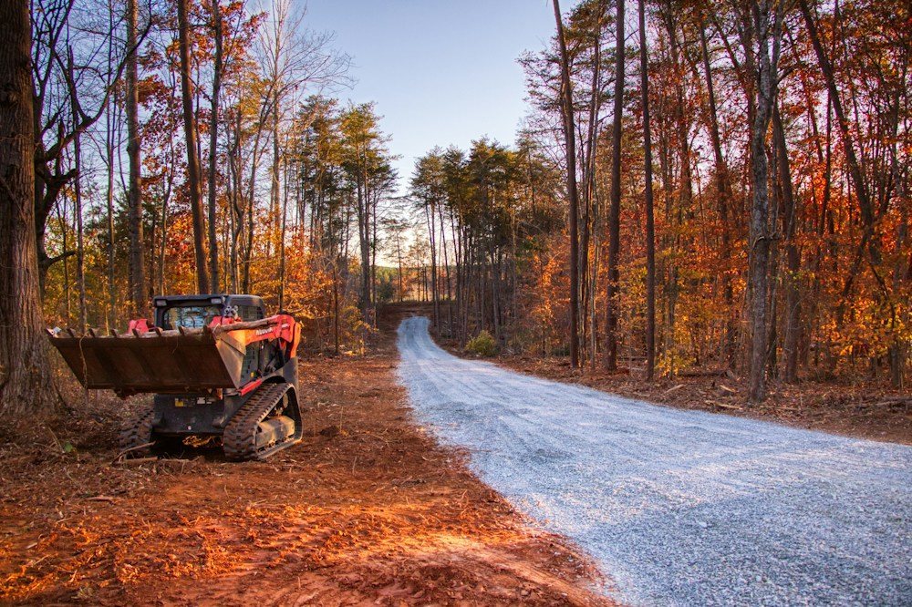A skid steer with a forestry mulcher attachment clearing brush and saplings